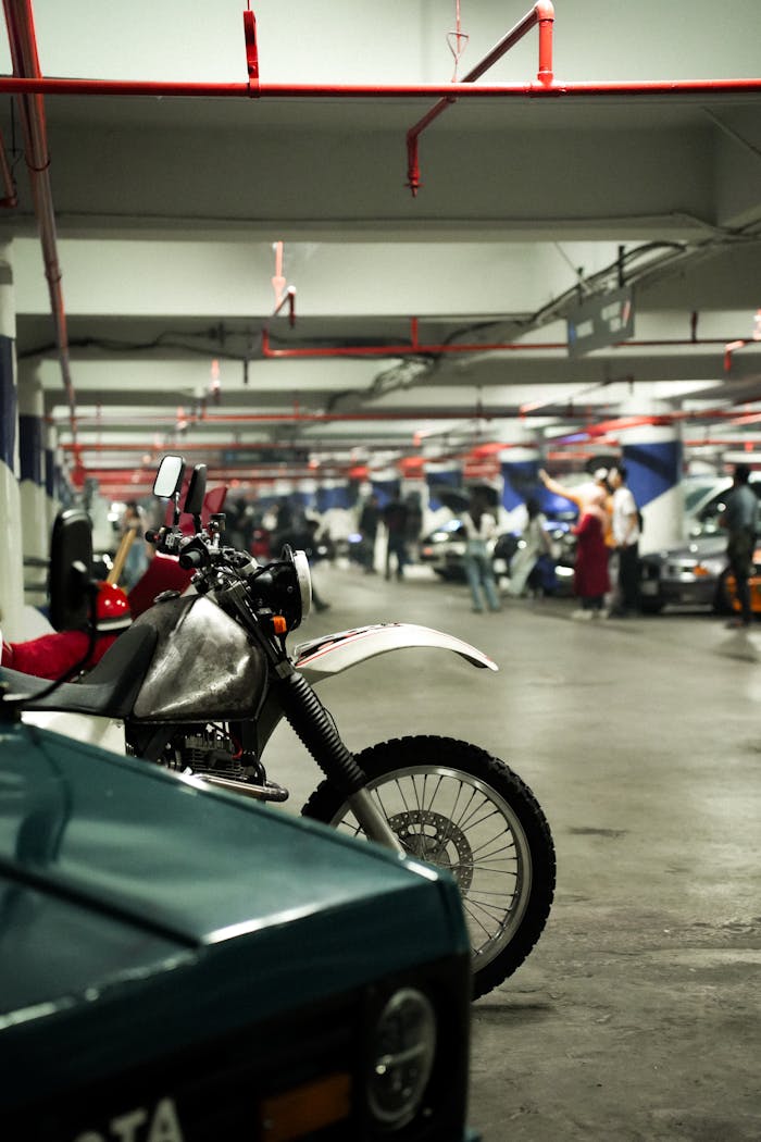 Motorbike parked in an indoor garage with people and cars in the background.